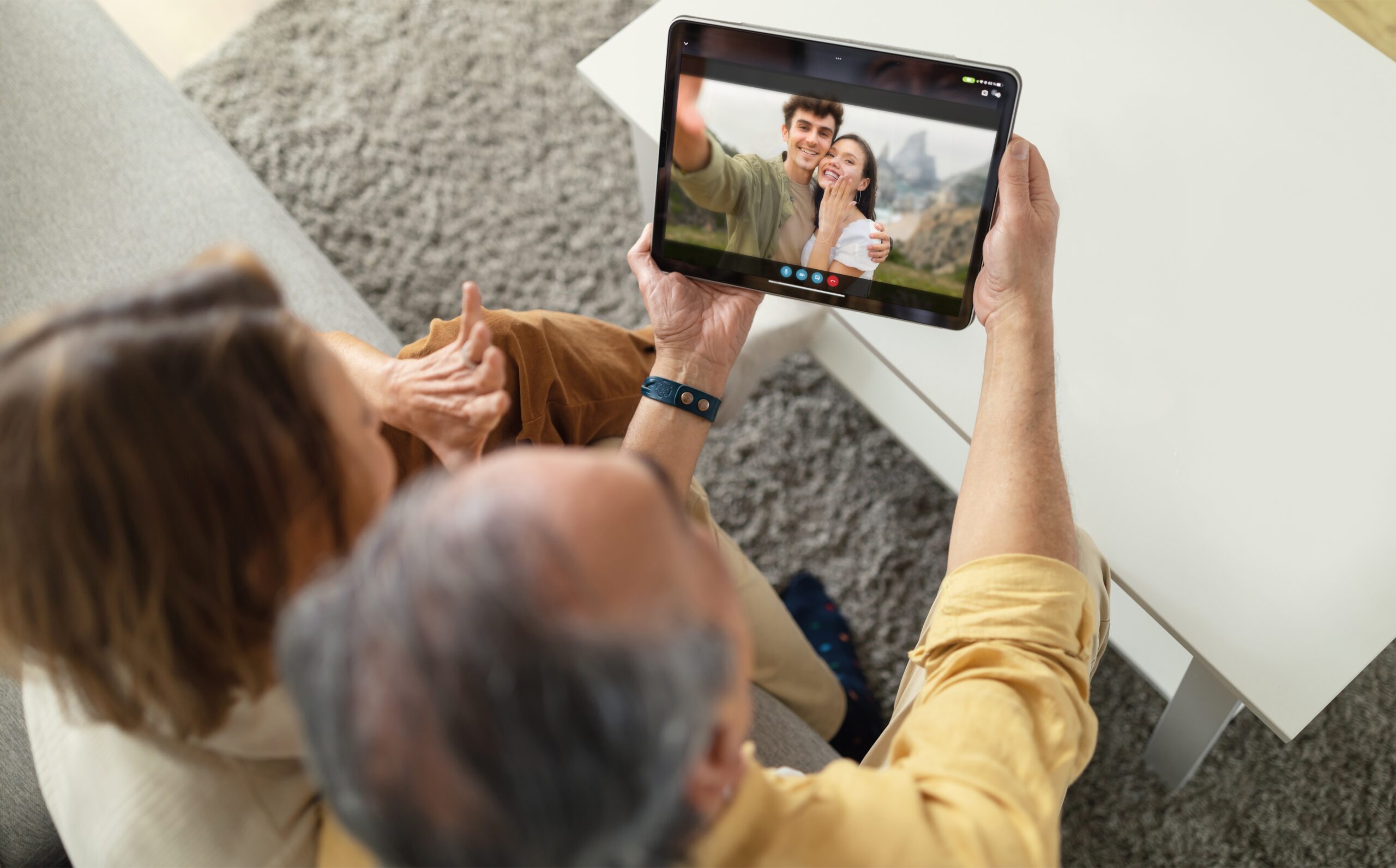 Foto van grootouders die via een videogesprek op een tablet met hun zoon en schoondochter praten 
