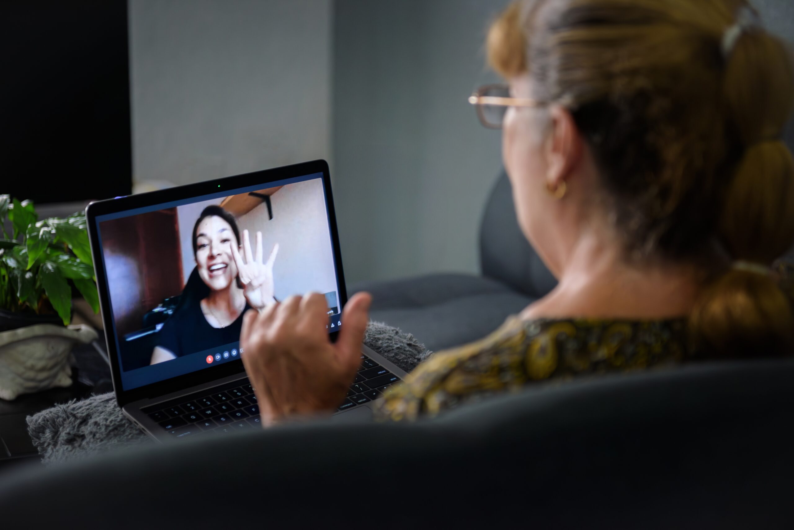Foto van een dame van in de zestig die via een laptop via videoconferentie met haar dochter praat 